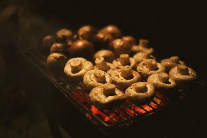 Mushrooms on a grill above glowing coals