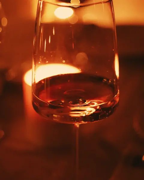 A glass of red wine lit by a candle