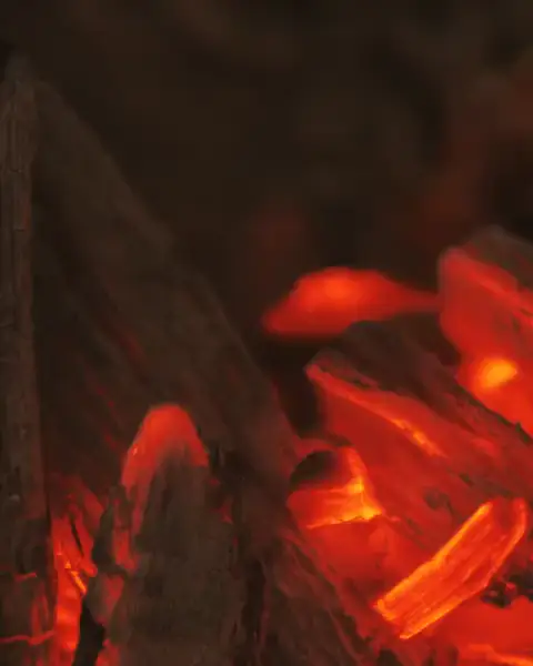 Charcoal glowing red under a thin flame